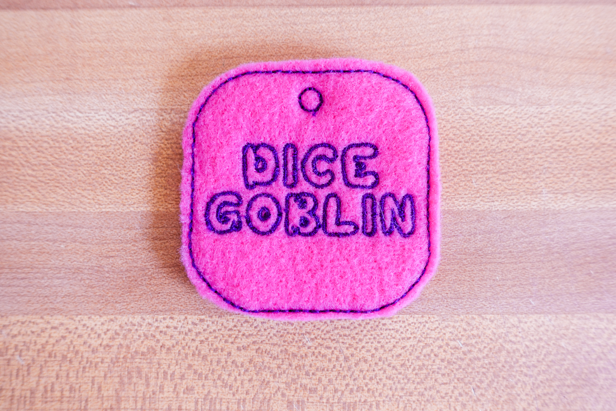 closeup view of the dice bag tag, pink, with the words “Dice Goblin”