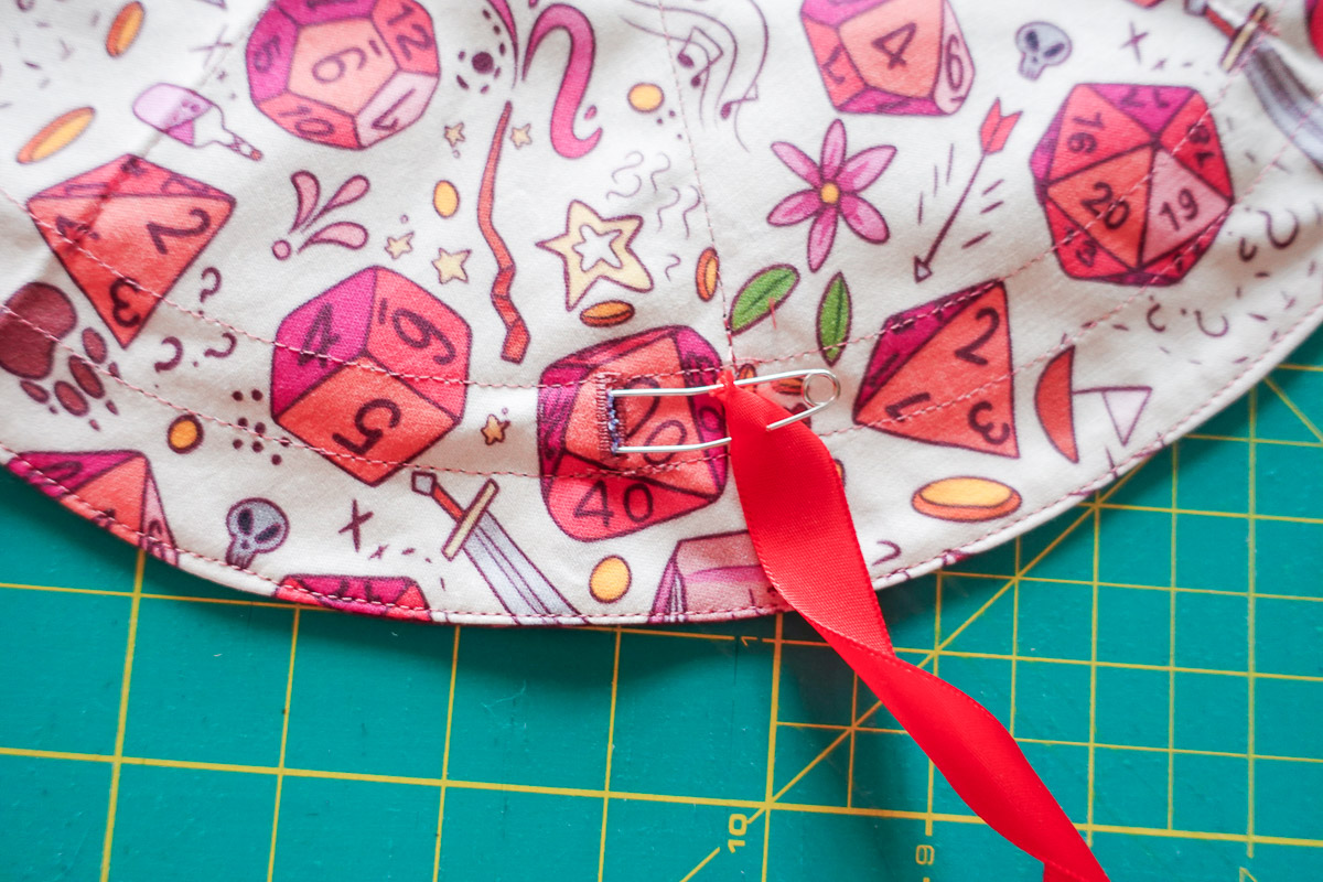 Colorful fabric with a red ribbon being inserted into the channel with a safety pin