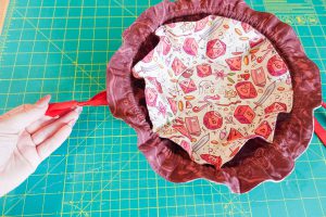 A hand holding red ribbon and cinching it around the finished DND Dice Bag