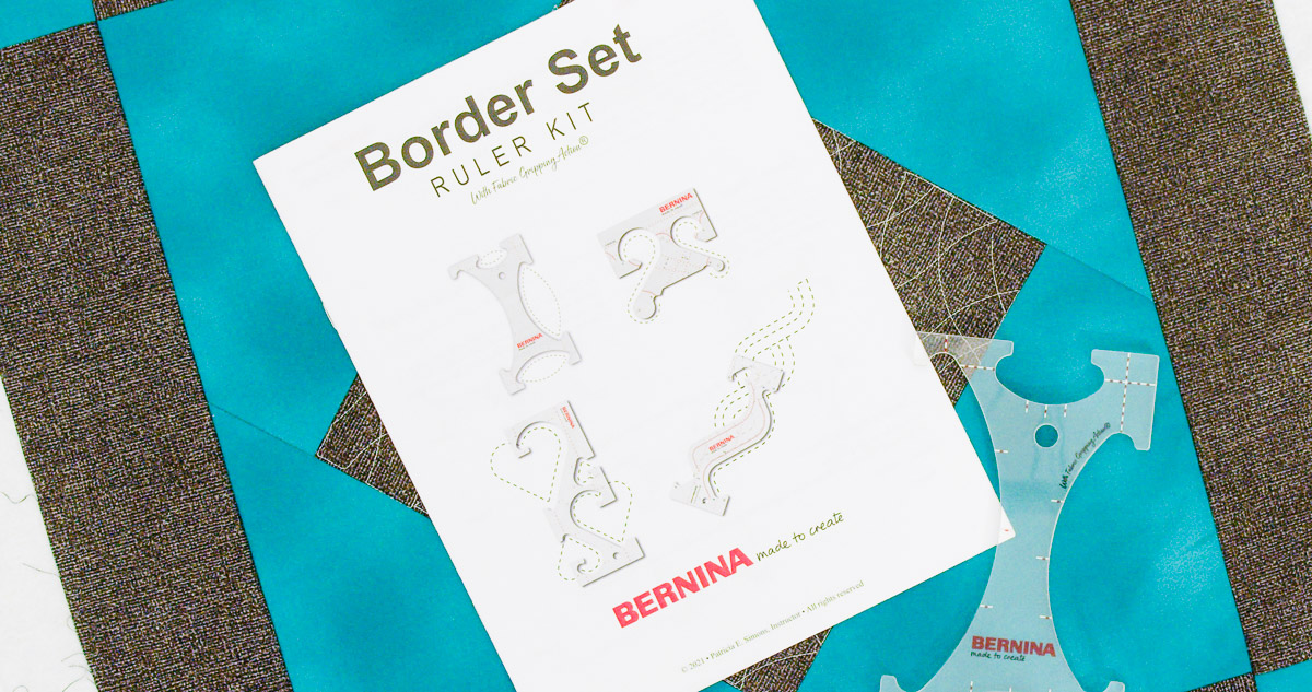 Overhead view of teal and gray fabric with the manual and Arch Ruler from the BERNINA Border Set Ruler Kit