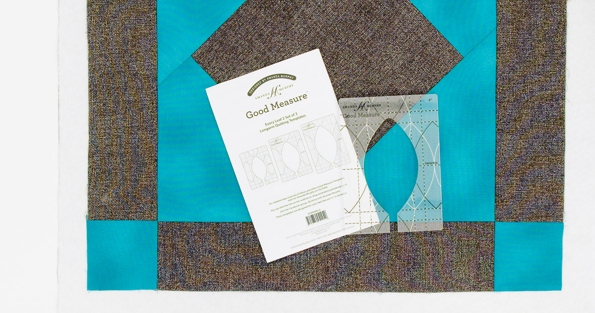 Overhead view of teal and gray fabric with the manual and Leaf Ruler from Amanda Murphey’s Good Measure set