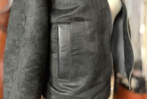 A close up image of a smooth grain leather welt on a black suede jacket