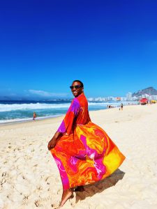 Black man on a beach wearing a colorful duster