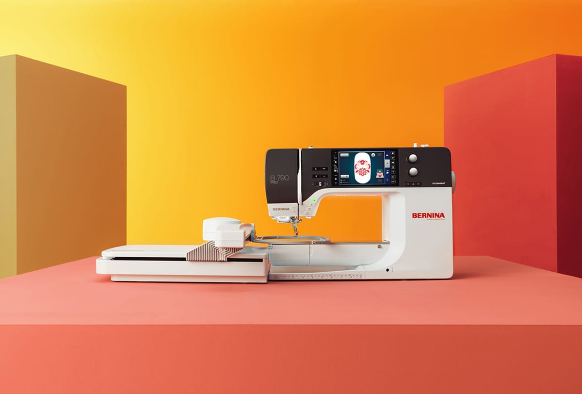 B 790 PRO sewing machine with embroidery module on an orange background