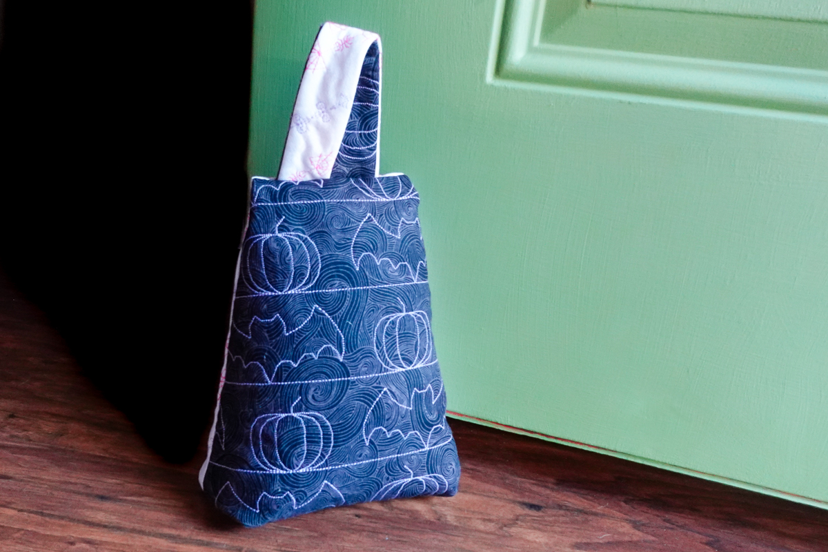 Halloween doorstop with bats leaning against a green door