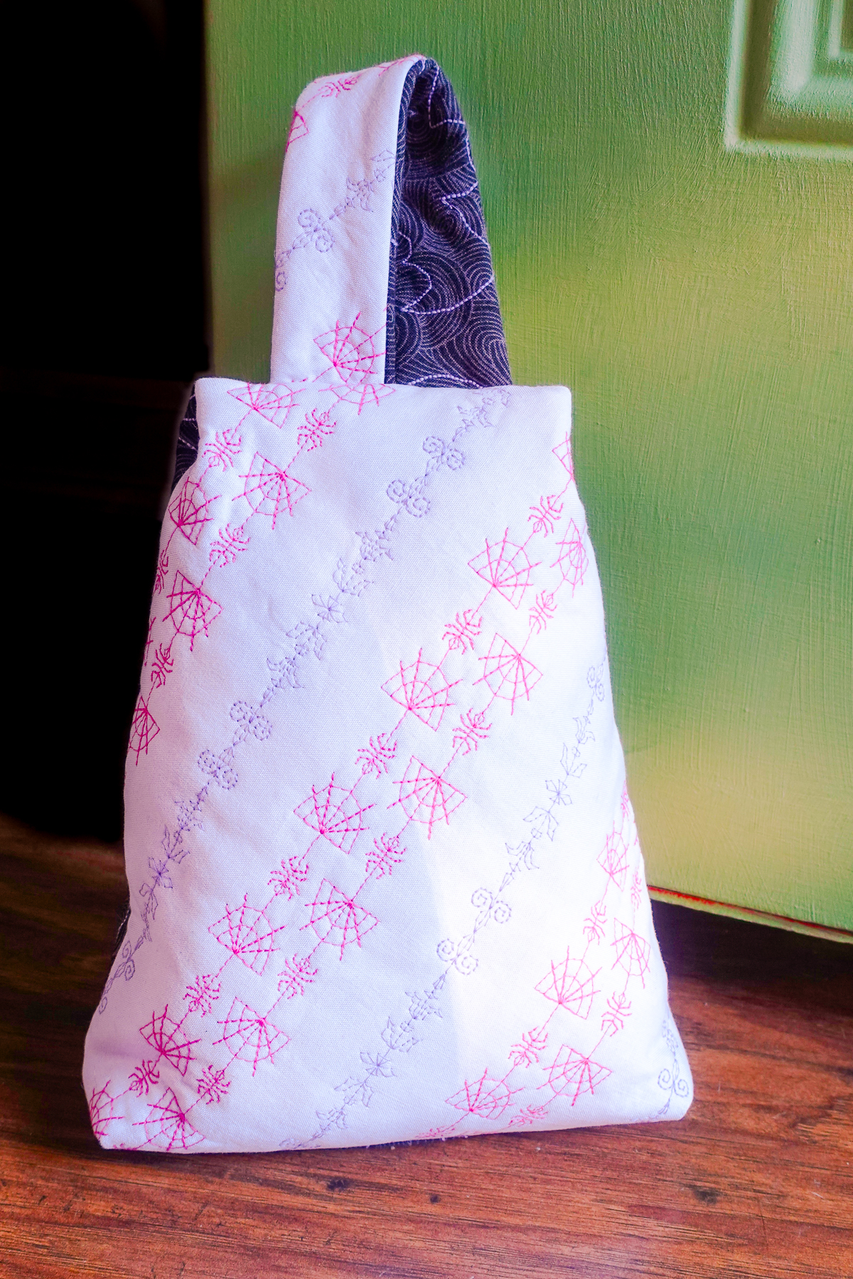 Halloween doorstop with white fabric and spider webs leaning against a green door