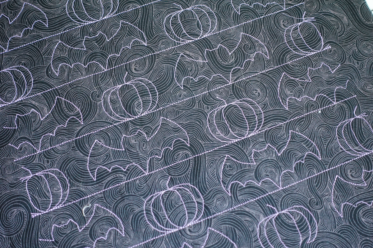 Pumpkins and bats embroidered on black fabric