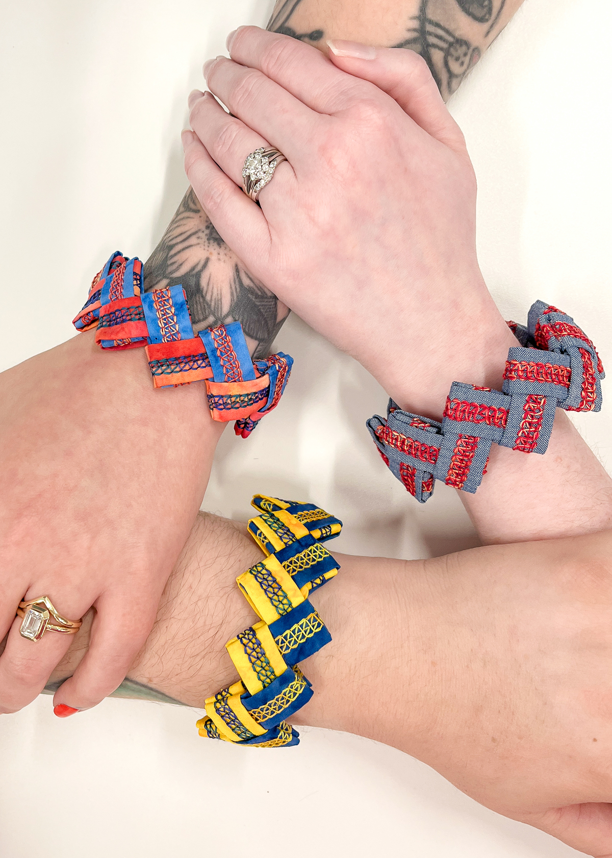Three wrists displaying serger cuff bracelets in various colors