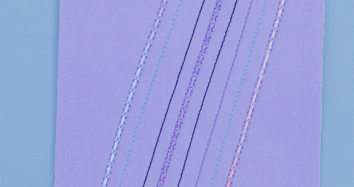 Completed purple fabric sample showing diagonal lines of couched variegated cording in multiple colors