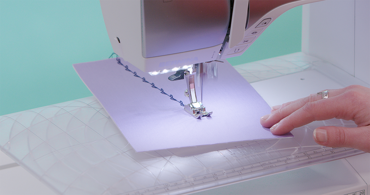 BERNINA sewing machine stitching decorative patterns on purple fabric using Cordonnet Foot #11