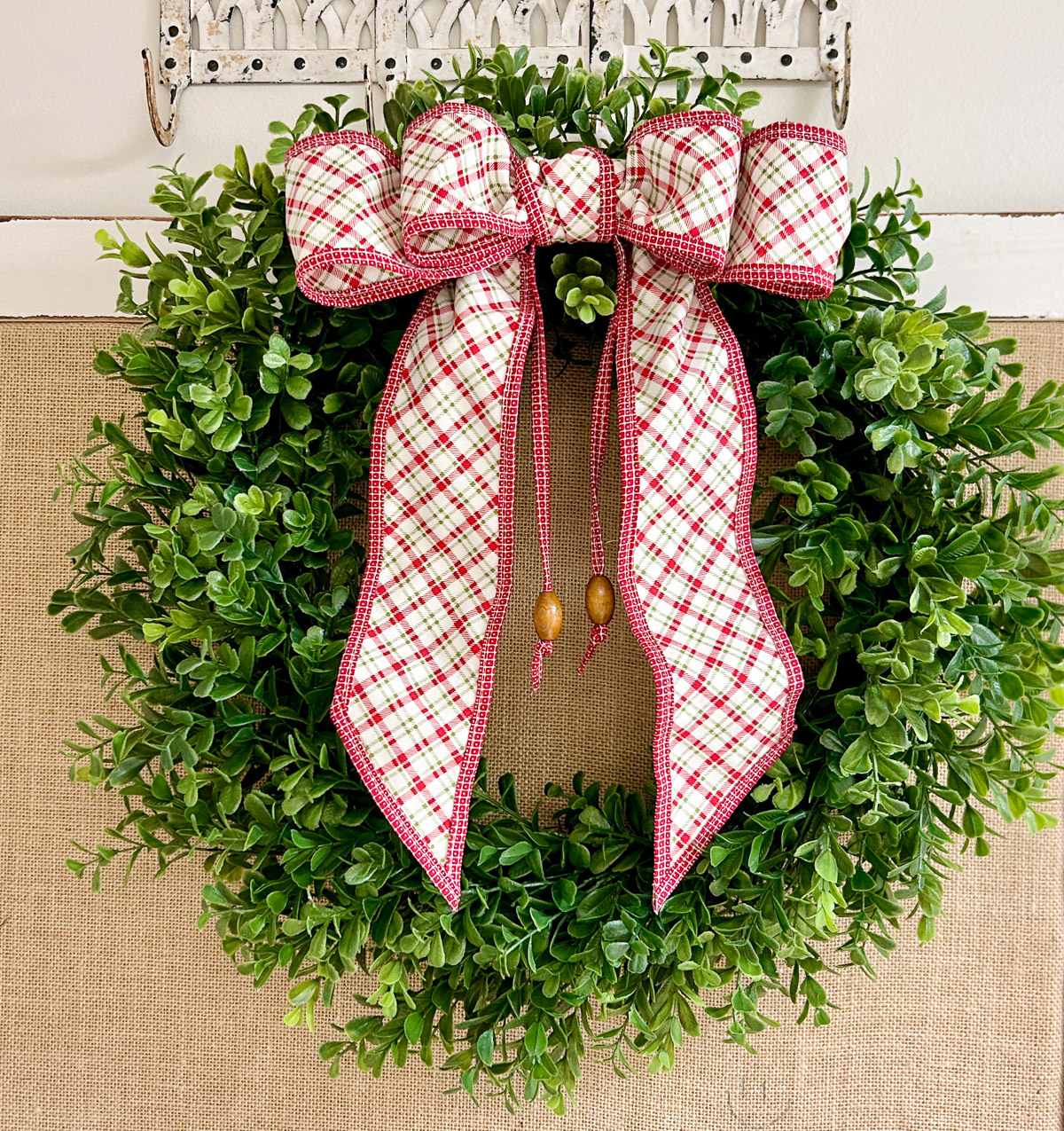 green wreath with a red plaid wired bow.