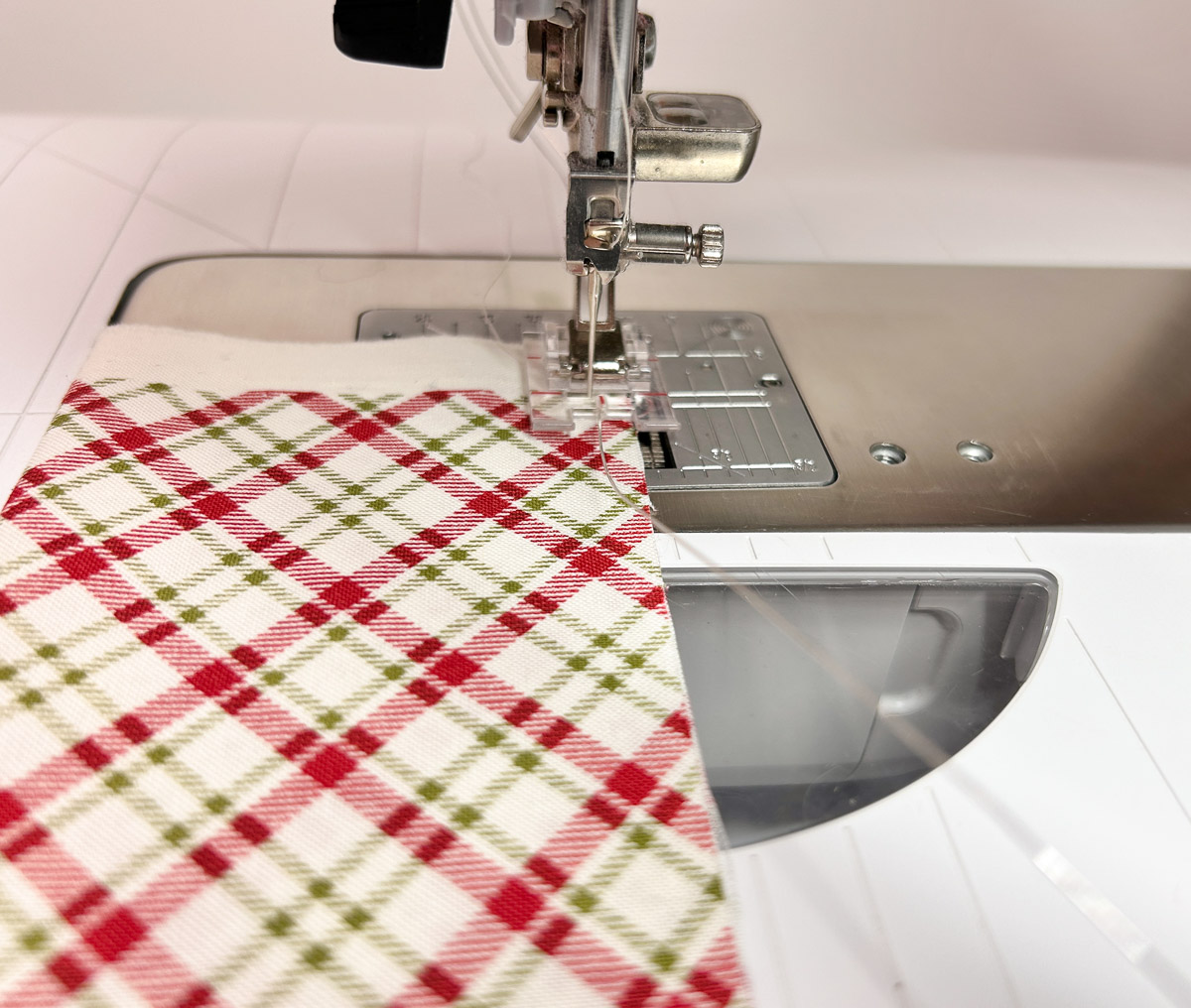 red plaid fabric being fed through the sewing machine, with wire sewn on.