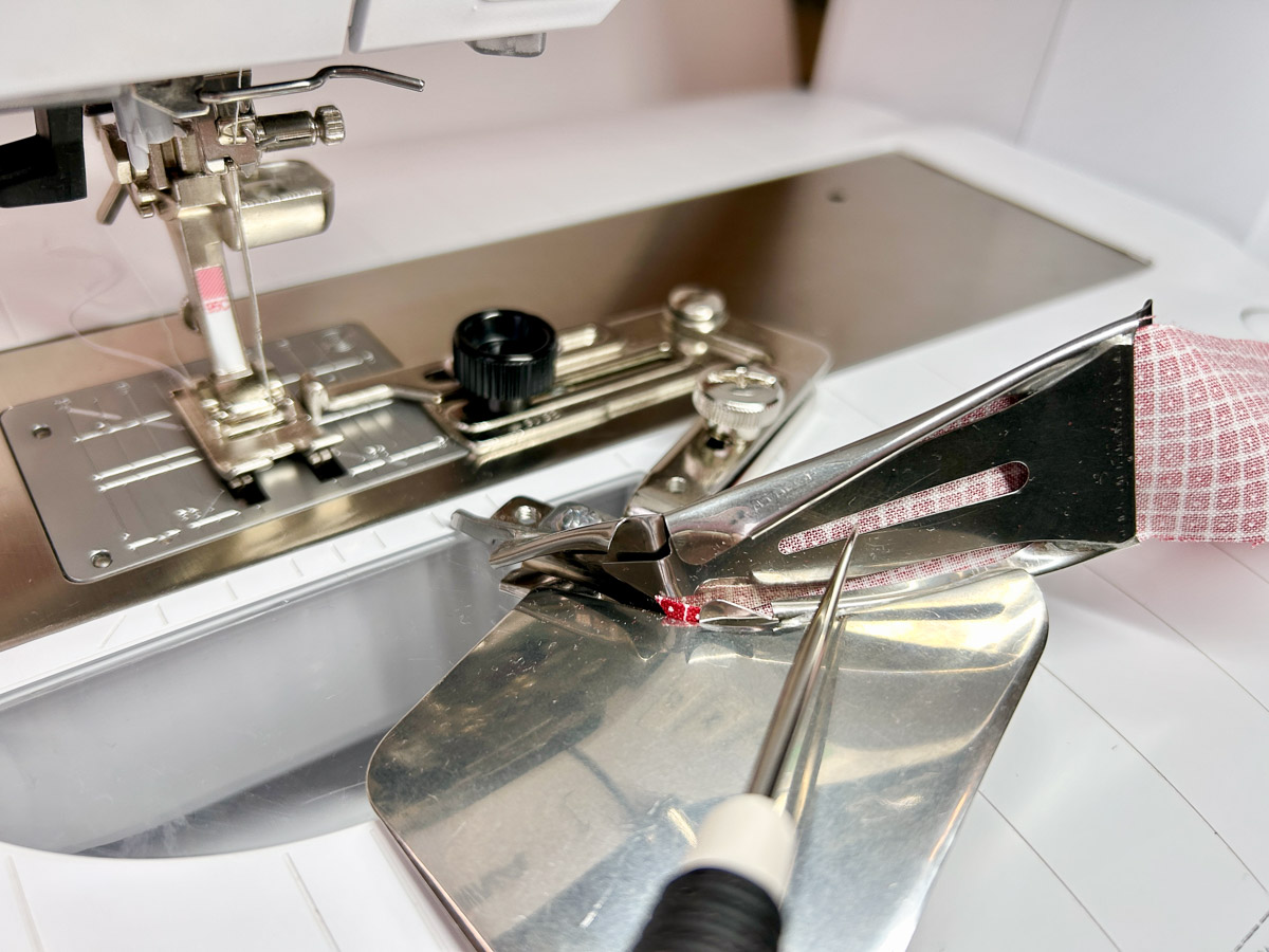 close up view of feeding red binding through a binder attachement.