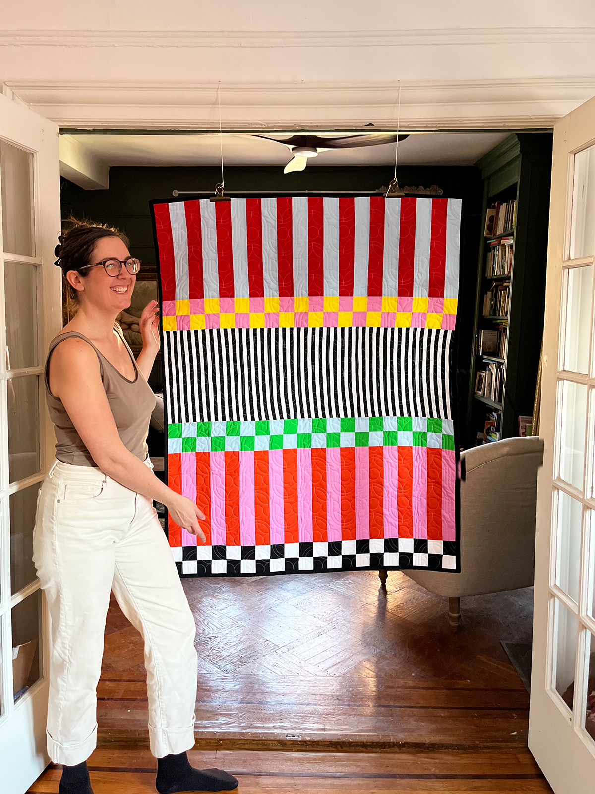 BERNINA ambassador Jaclyn Salem stands in front of the finished Checks Mix quilt—a free quilt pattern.