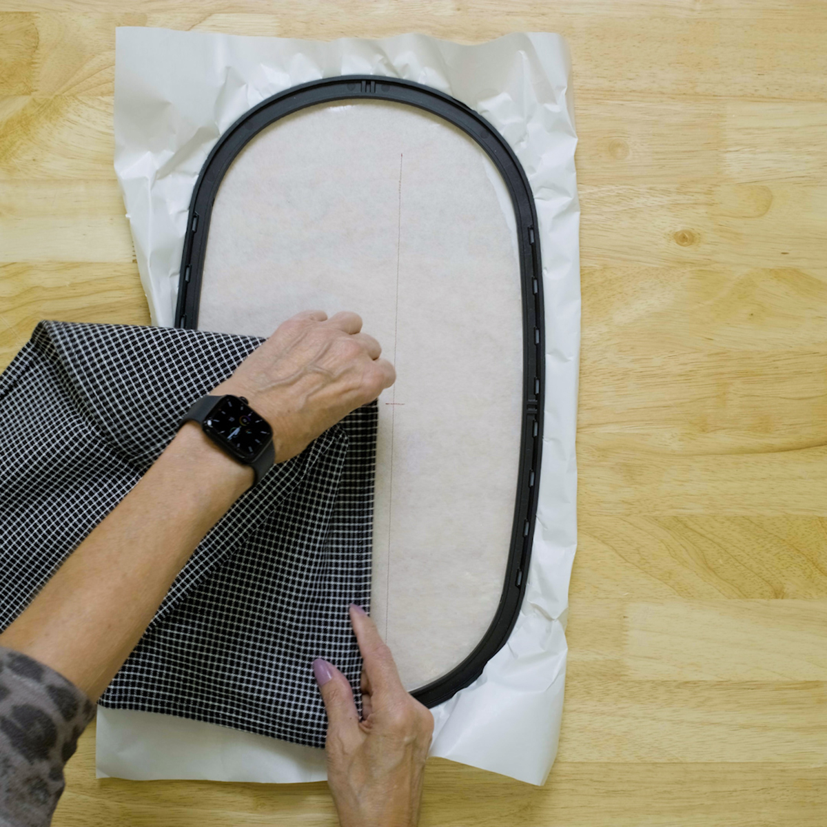 overhead view of a towel being aligned to the stitched placement line on hooped stabilizer