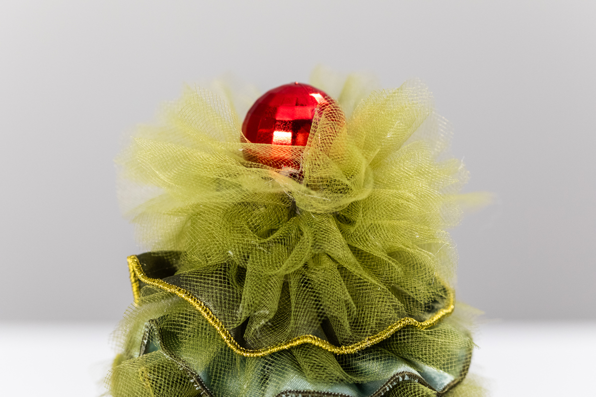 green fabric and tulle tree with red ball on top