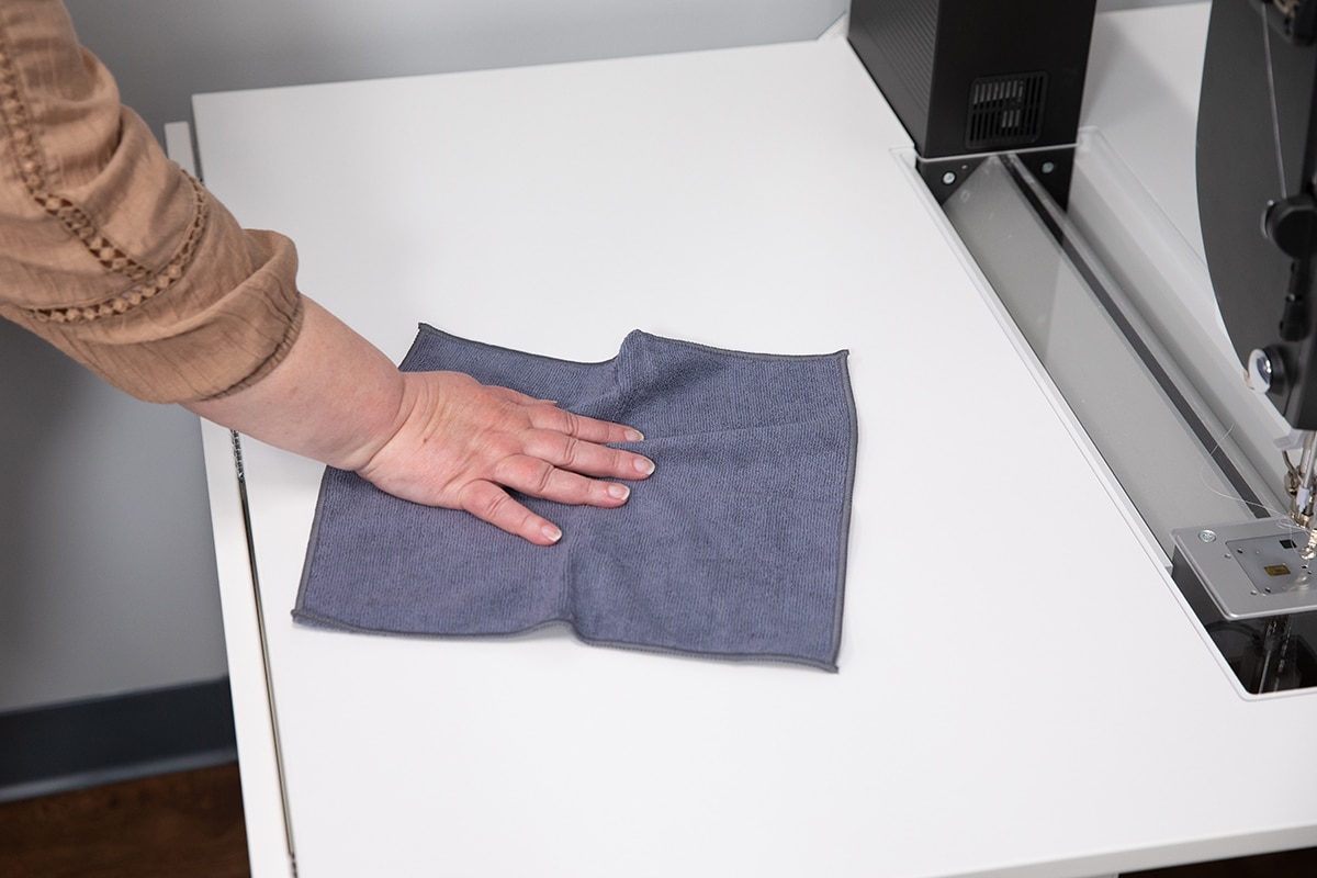 woman’s hand wiping table with gray cloth
