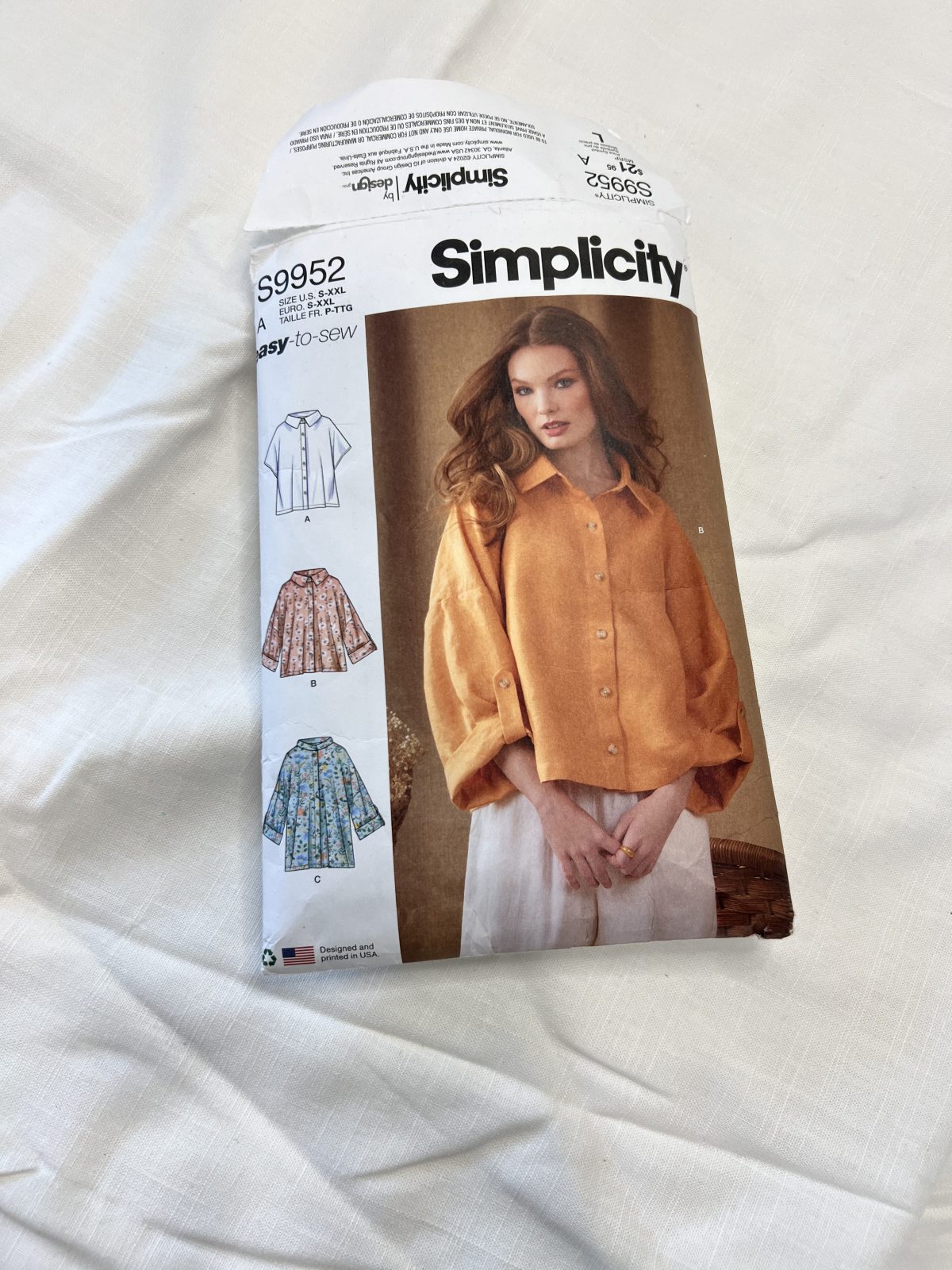 Simplicity S9952 easy-to-sew sewing pattern displayed on white linen fabric, featuring a relaxed button-front collared shirt in multiple sleeve lengths.