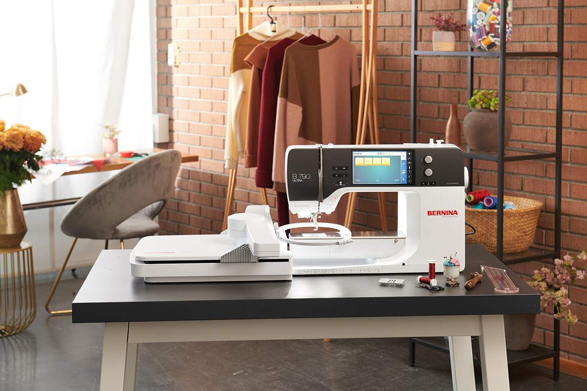 Computerized sewing machine with embroidery module placed on table in a cozy, creative loft-style sewing room.