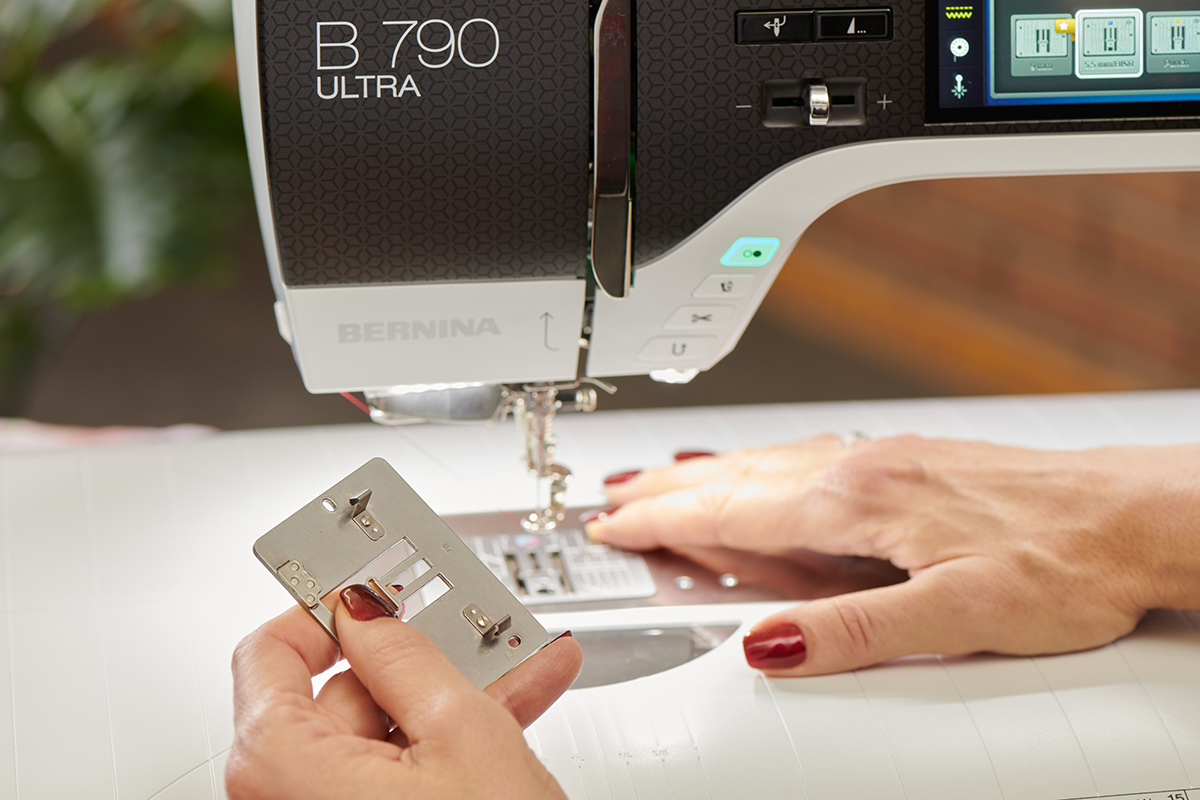 Close up image of a sewing machine's metal stitch plate. The underside of the plate shows a small sensor.