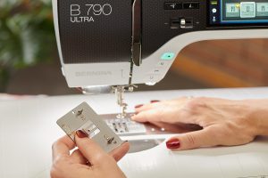 Close up image of a sewing machine's metal stitch plate. The underside of the plate shows a small sensor.
